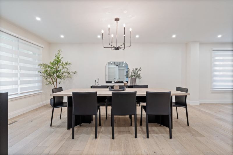 Separate dining room with a table for eight, a modern black chandelier and light hardwood floors