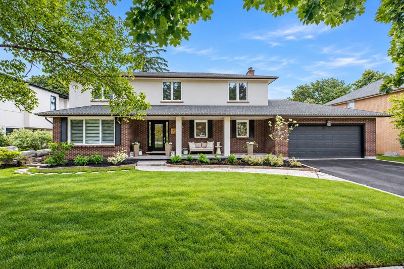 Front exterior of 7 Carl Crescent: a two-storey brick and stucco home with a covered porch, double garage and landscaped front lawn