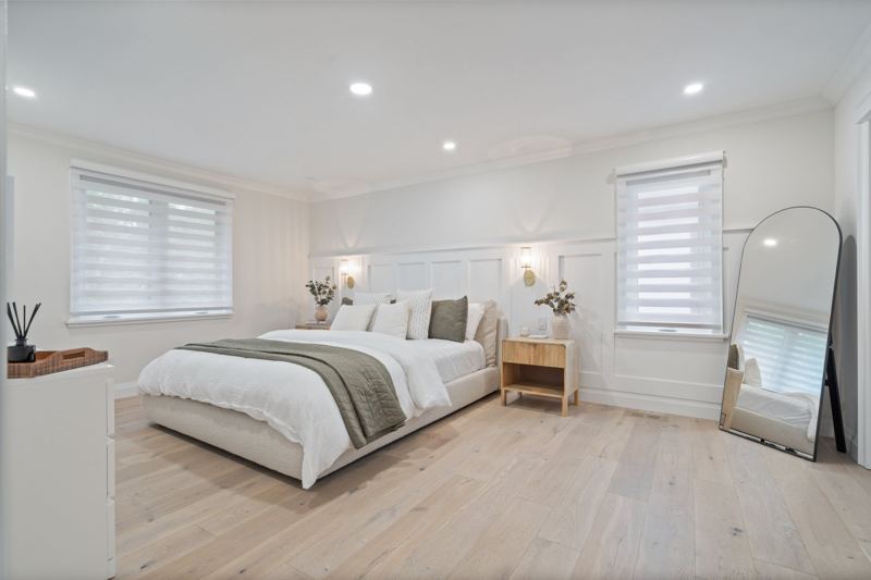 Primary bedroom with panelled feature wall, wall sconces, a queen bed and large windows