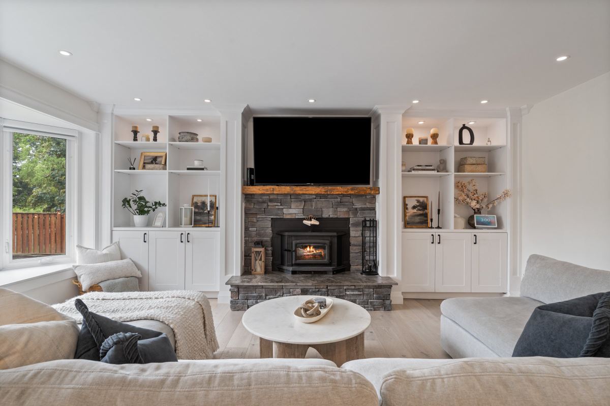 Living room with a stone wood-burning fireplace, built-in white shelving on both sides and a sectional sofa